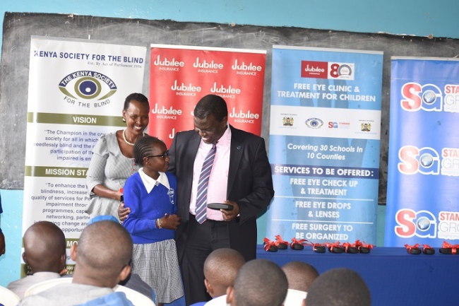  Dr. Julius Kip'ngetich, Regional CEO of Jubilee Insurance, hands out spectacles to a pupil. 