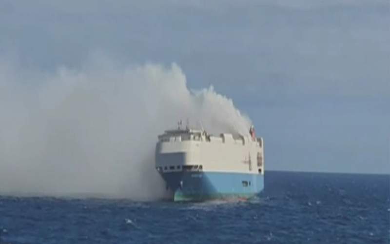 A cargo ship full of luxury cars on fire in the middle of the Ocean