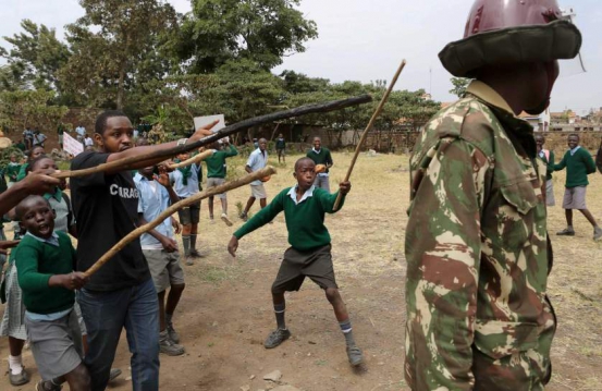 Kenyan school pupils and activists challenge riot police during a protest against the removal of their