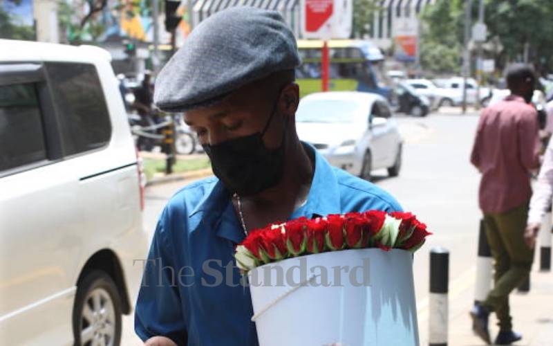 Man walking along Muindi St. with a bouquet.
