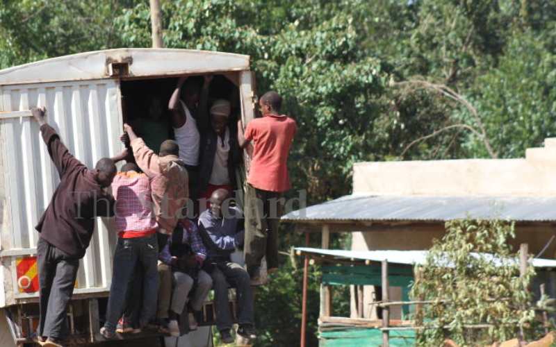 Men hanging on a lorry along Igare-Itumbe Rd