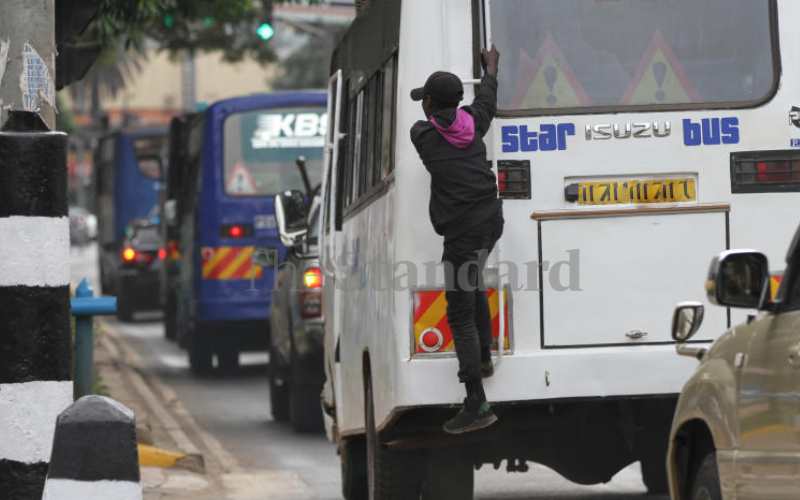 Man hanging on a bus along Kenyatta Avenue