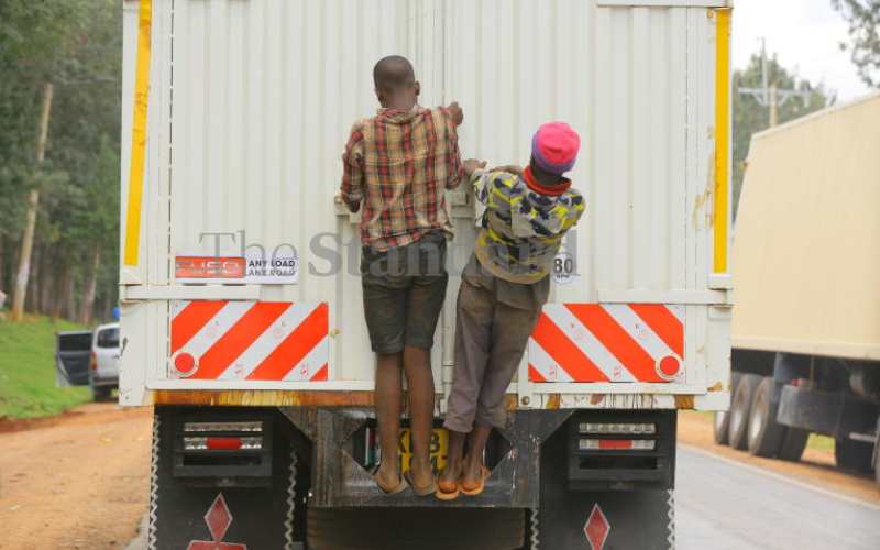 Boys hang on a lorry along Kisii-Keroka Road
