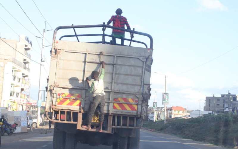 Youths hang on a lorry along Kangundo Road 