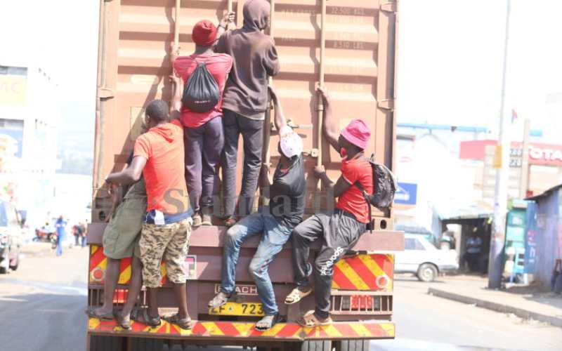 Men hang on a trailer along Obote Rd, Kisumu