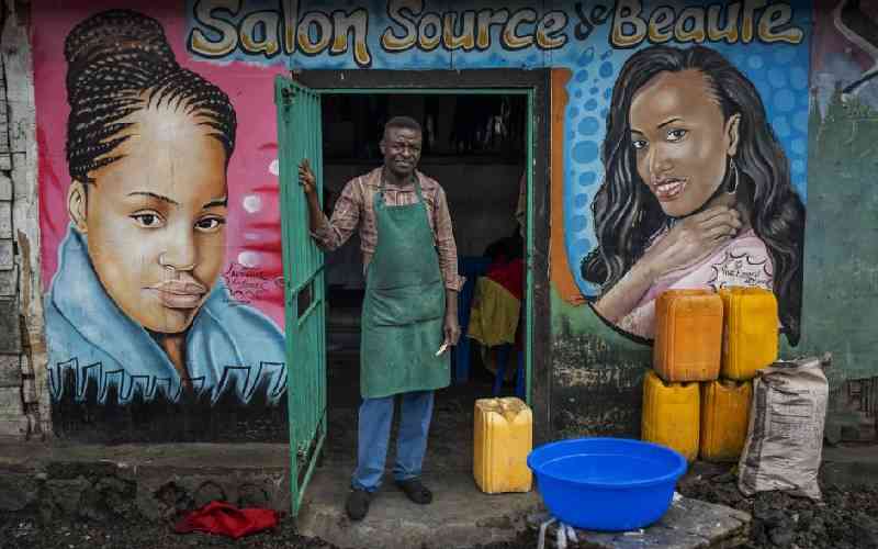Mohimbo, 48, poses in front of his salon in Goma.