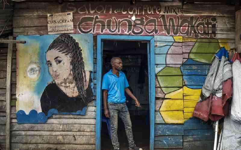 Kagheni, 30, poses in front of his salon in Goma.