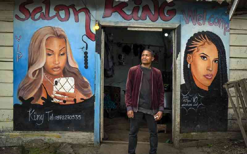 Clovis, 22, poses in front of his salon in Goma.