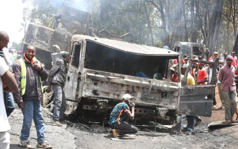 Residents examining charred shell of the truck.