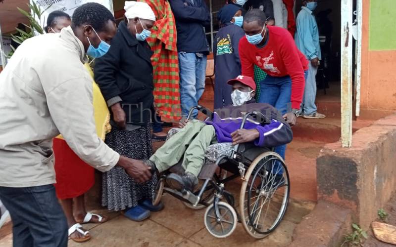 Person with disability being assisted in Muguga