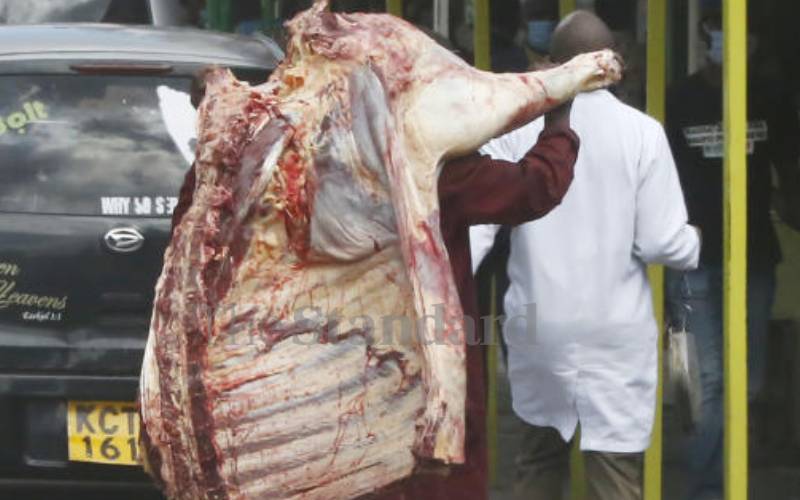 Meat trader navigating traffic at Nakuru City.