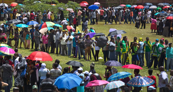 Mourners queue under the midday sun to get onto buses that will take them to view the casket of Nelson Mandela  lying in state for the second day in Pretoria. Below Left: A woman cries after paying her respects. Below Right: South African expatriates listen to a eulogy during a memorial service at St George Church in Singapore. [PHOTOS: REUTERS]