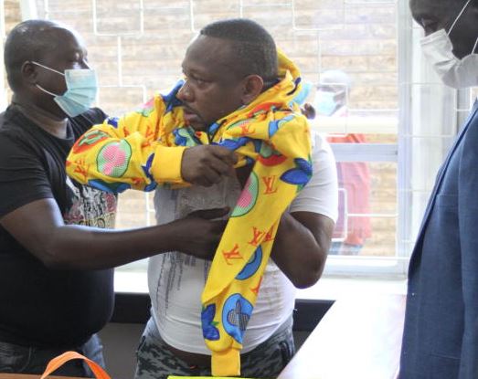 Sonko is assisted into a new jacket. 