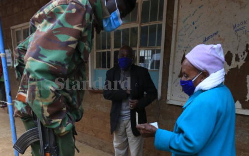 Policeman assisting an elderly voter at Karuri