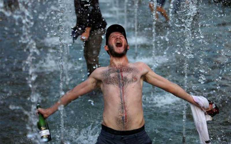 A France fan celebrate in a fountain after defeati