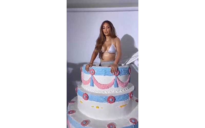 Kim Kardashian pops out of a tiered birthday cake wearing a bikini